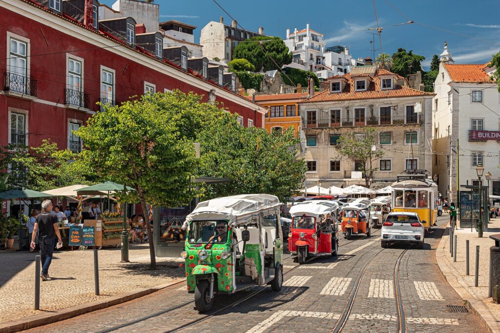 Colorful tuk-tuks on a bright Alfama street in Lisbon