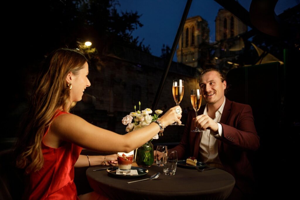 Couple dining with champagne on an evening Seine dinner cruise in Paris