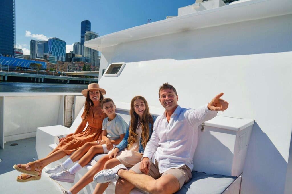 Family on catamaran river cruise with Brisbane skyline