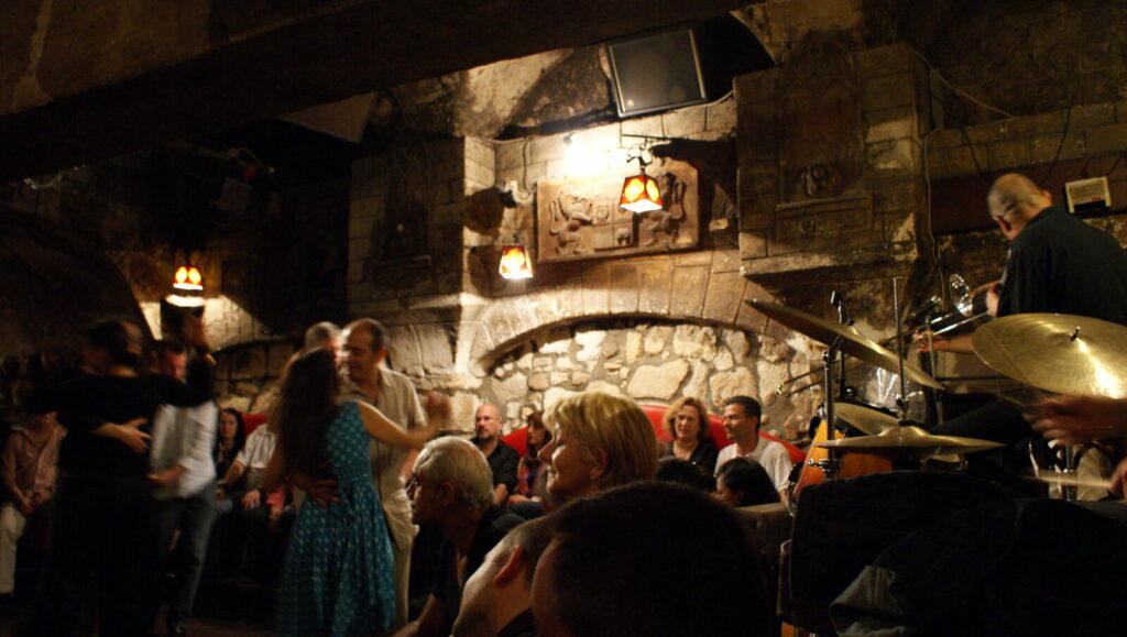 Live jazz band and swing dancers in the vaulted stone cellar of Caveau de la Huchette, Paris
