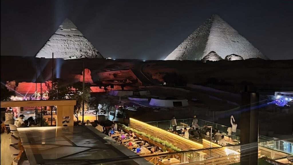 Dinner on a rooftop with the floodlit Giza pyramids behind