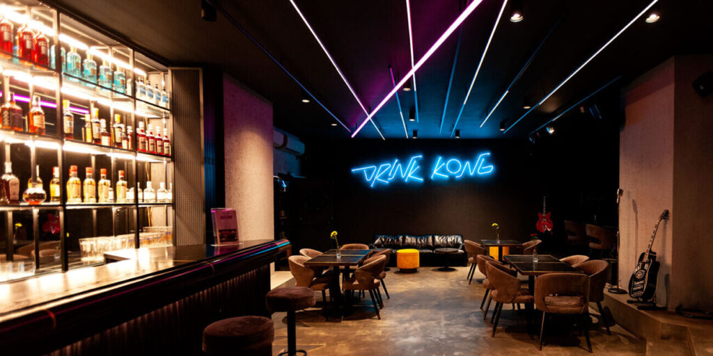 Neon-lit cocktail bar interior with DRINK KONG sign in Rome