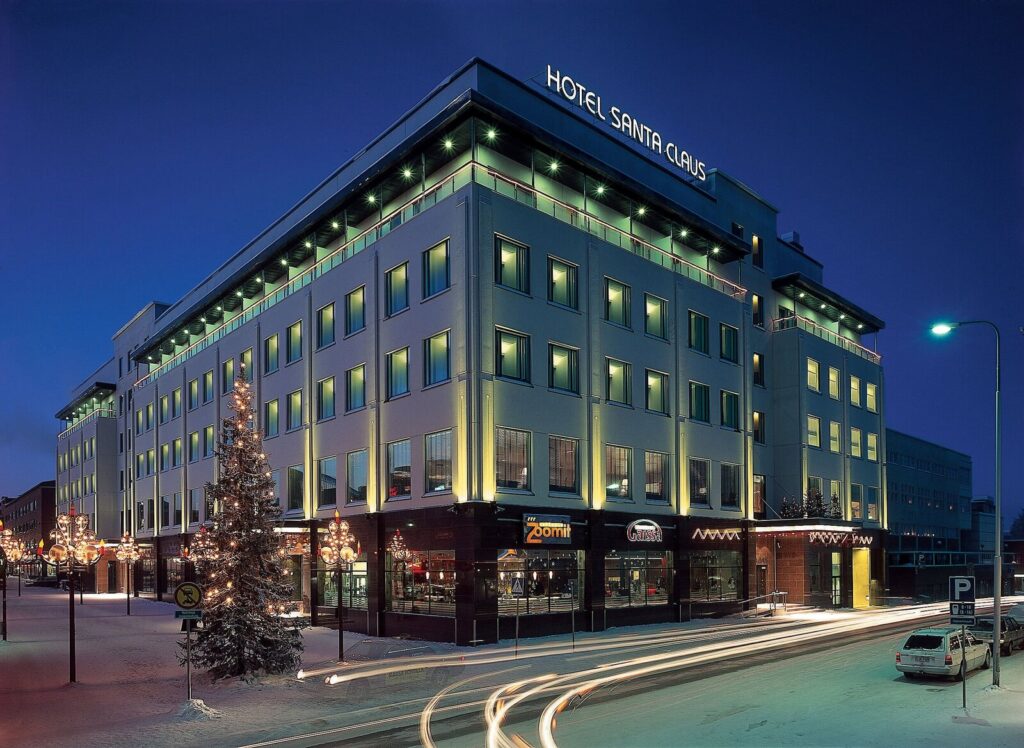 Illuminated Hotel Santa Claus facade at twilight with snow in Rovaniemi