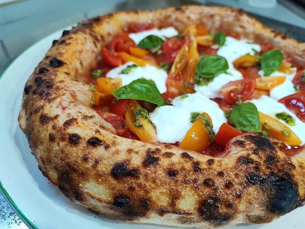 Wood-fired Neapolitan pizza with tomato, mozzarella and basil in Naples
