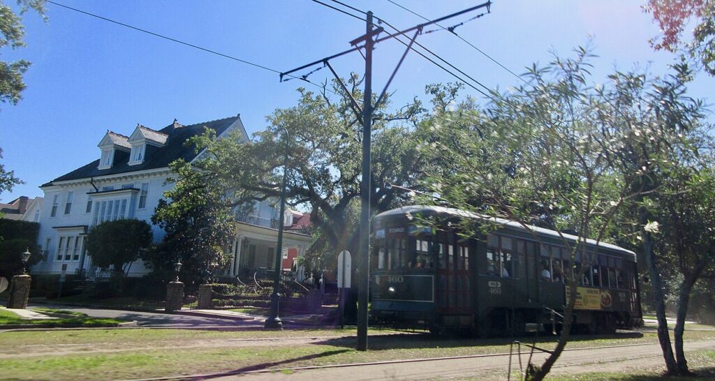 A green streetcar on oak-lined St. Charles Avenue in Uptown