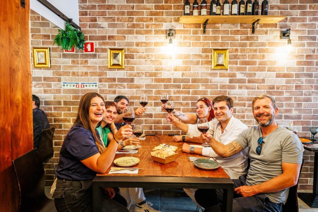 Group toasting wine at a table on a Lisbon food and wine tour