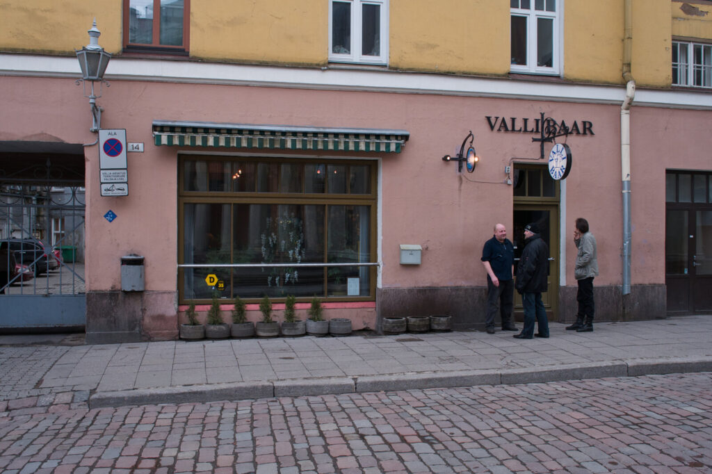 Pink facade of Valli Baar bar with people outside in Tallinn old town