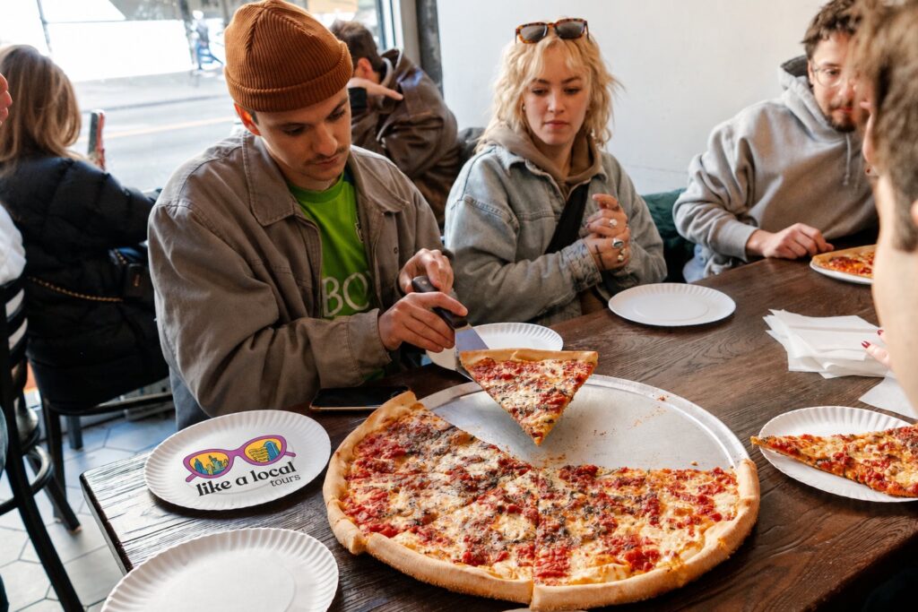 A Like A Local Tours group sharing a whole pizza at a neighborhood pizzeria